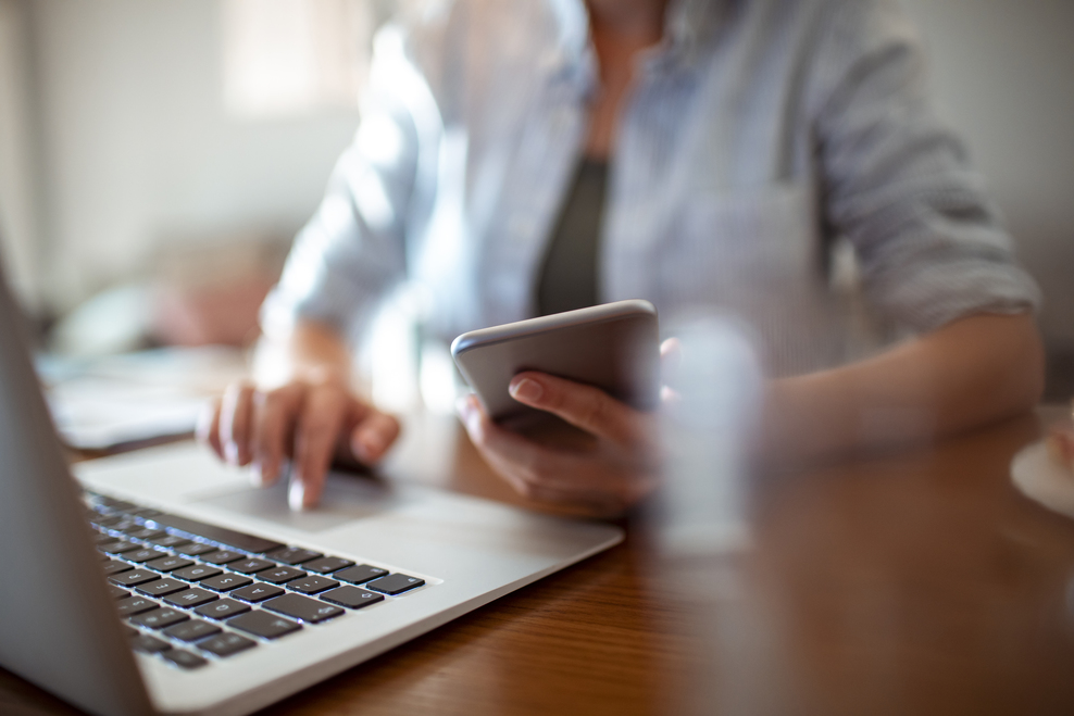 Frau tippt an Laptop und Smartphone